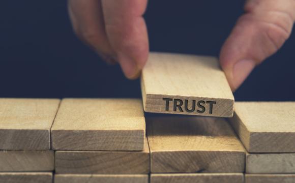 Building Trust concept, stack of wooden blocks with one with word trust being placed into open slot in stack